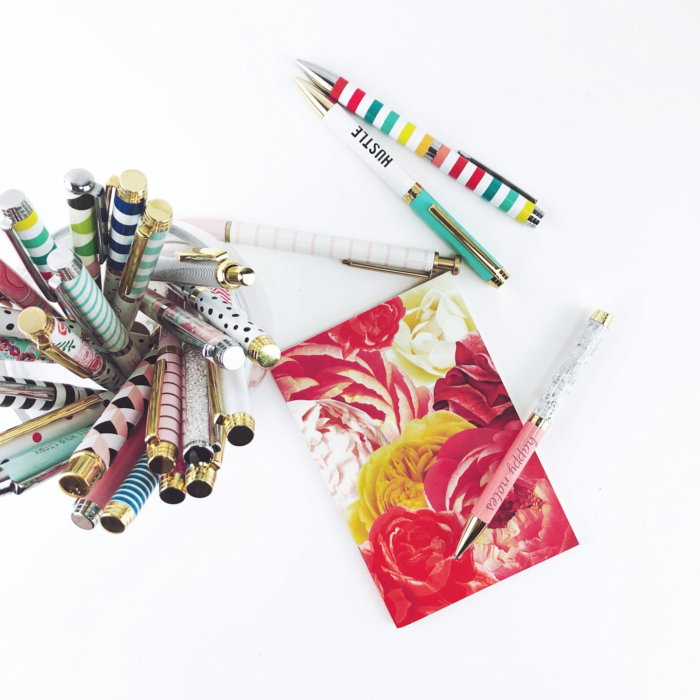 Patterned pens and a floral notebook sit on a table.