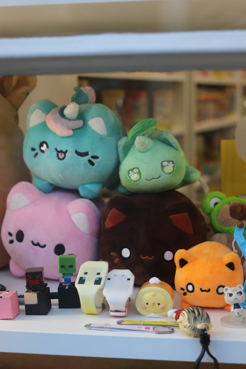 Plush cat toys and novelty items arranged on a shelf.