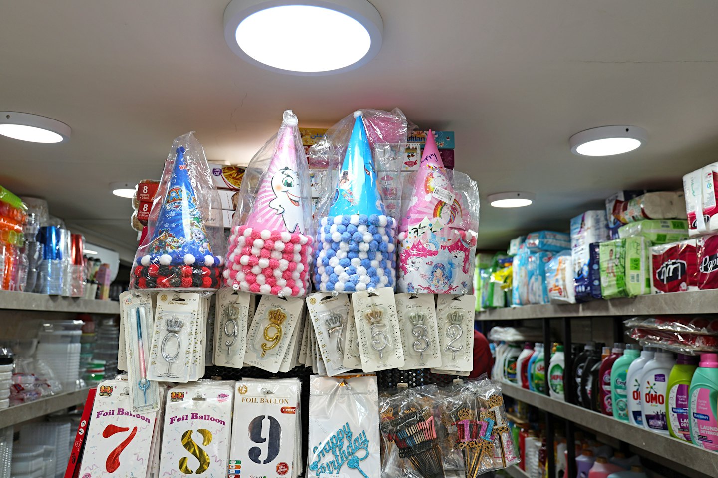 Party supplies including hats, candles, and balloons on store shelves.