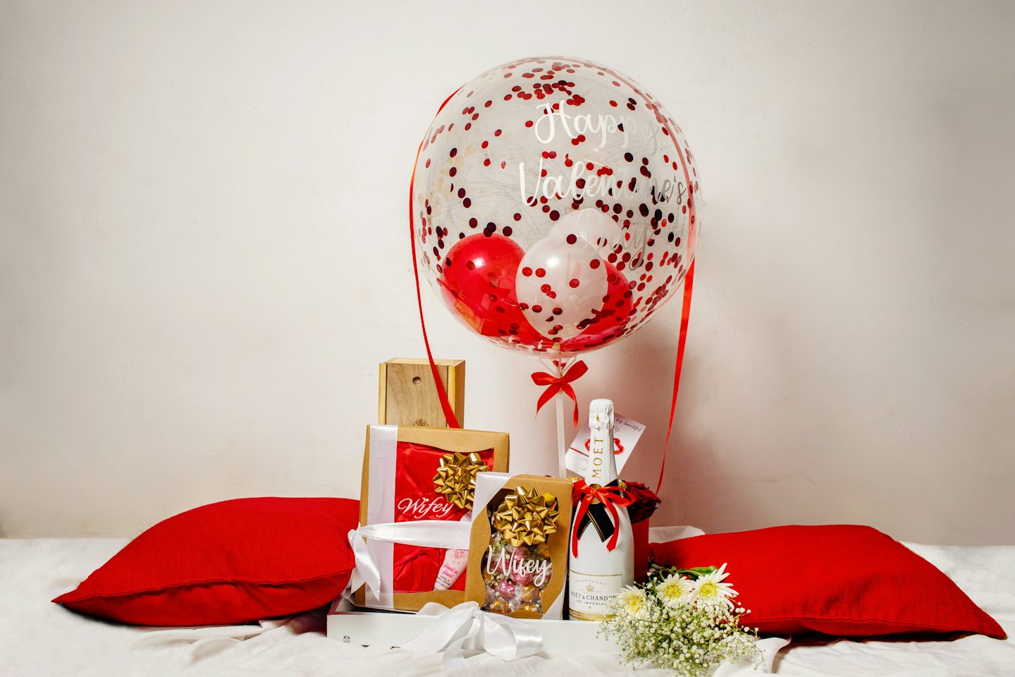 Valentine's gift arrangement with balloons, champagne, and flowers on a tray.
