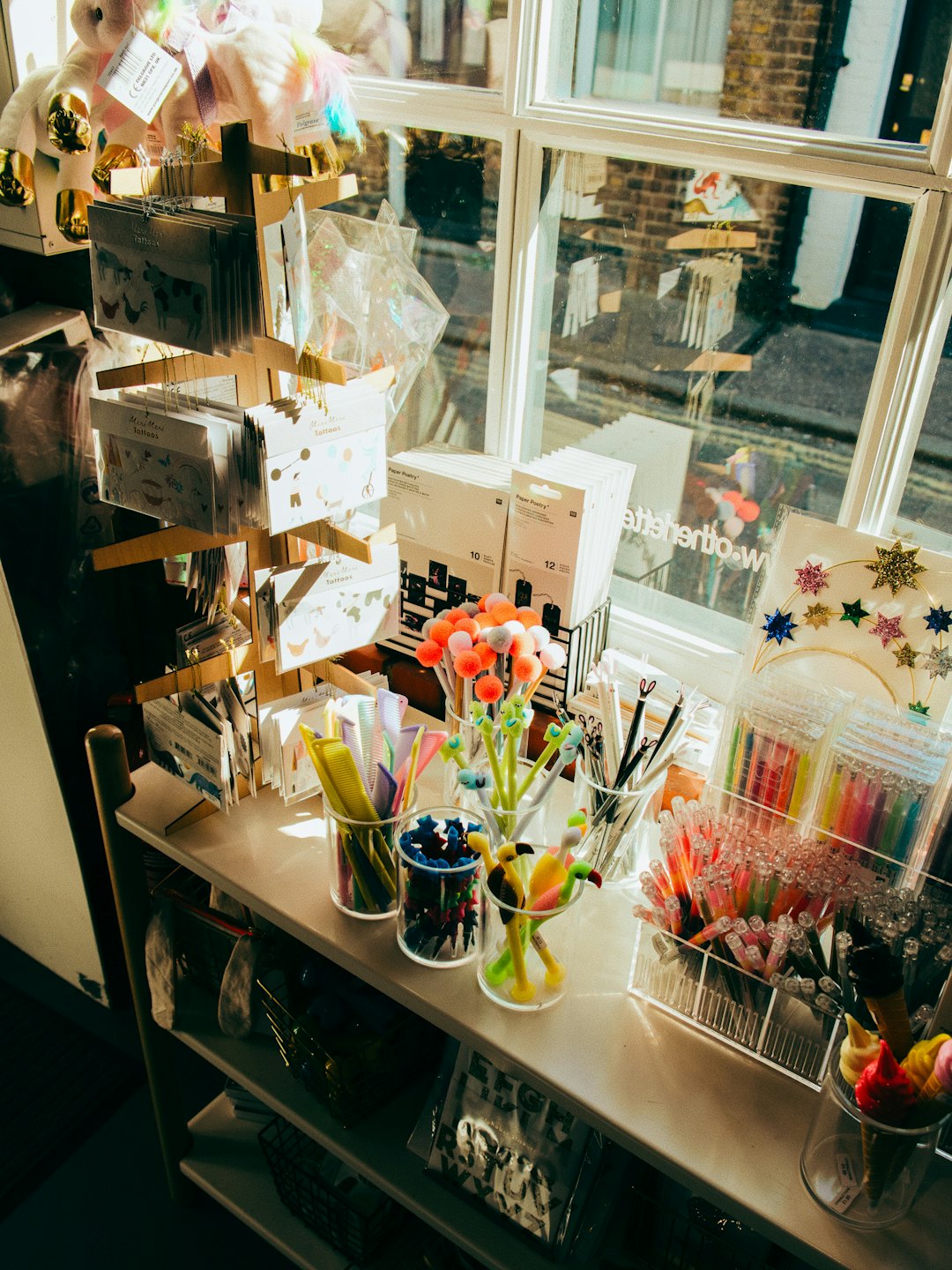 Colorful stationery and gifts displayed in a sunlit shop window.
